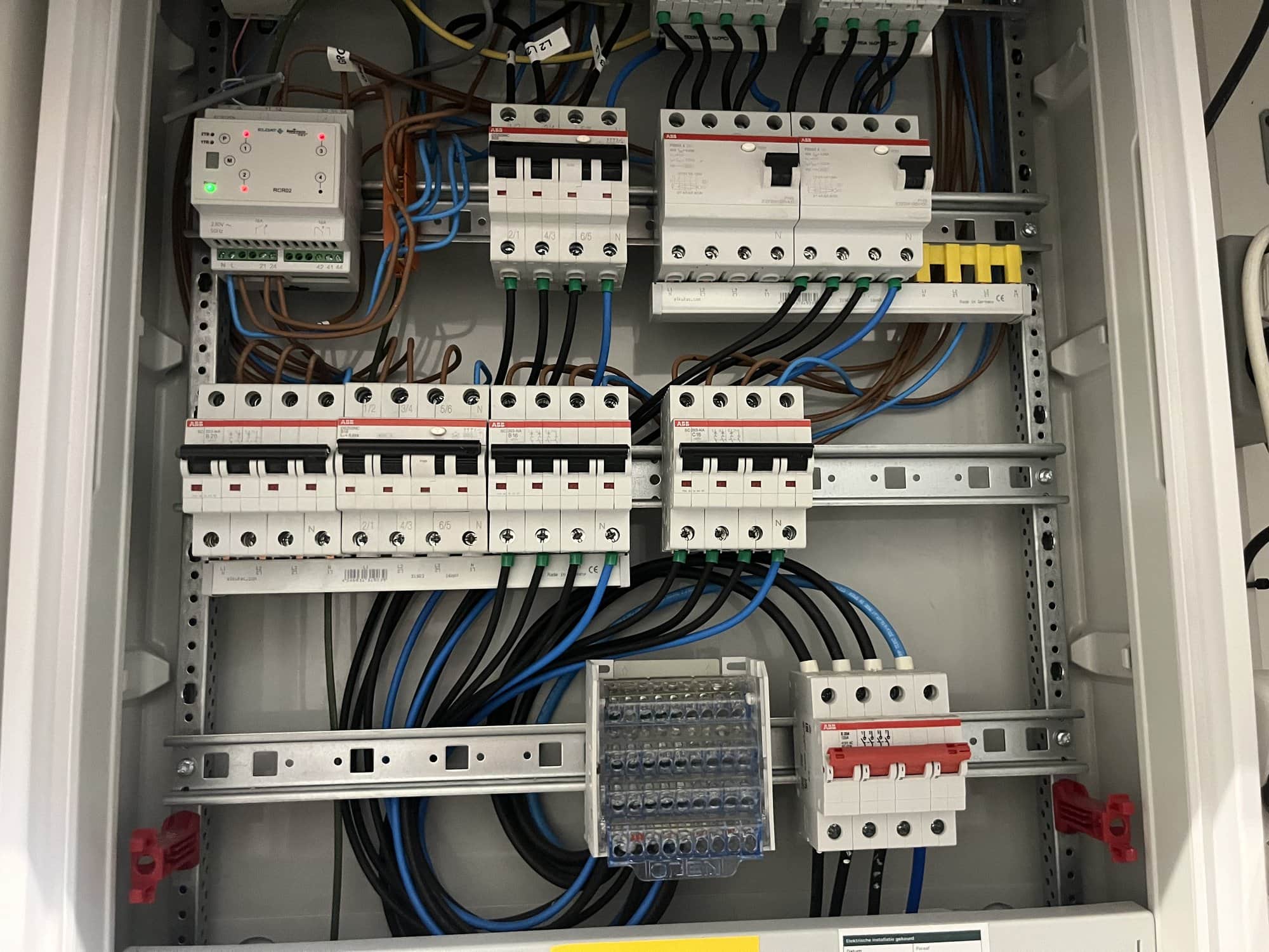 Geopende verdeelkast met nette bedrading en een relaismodule bovenin.